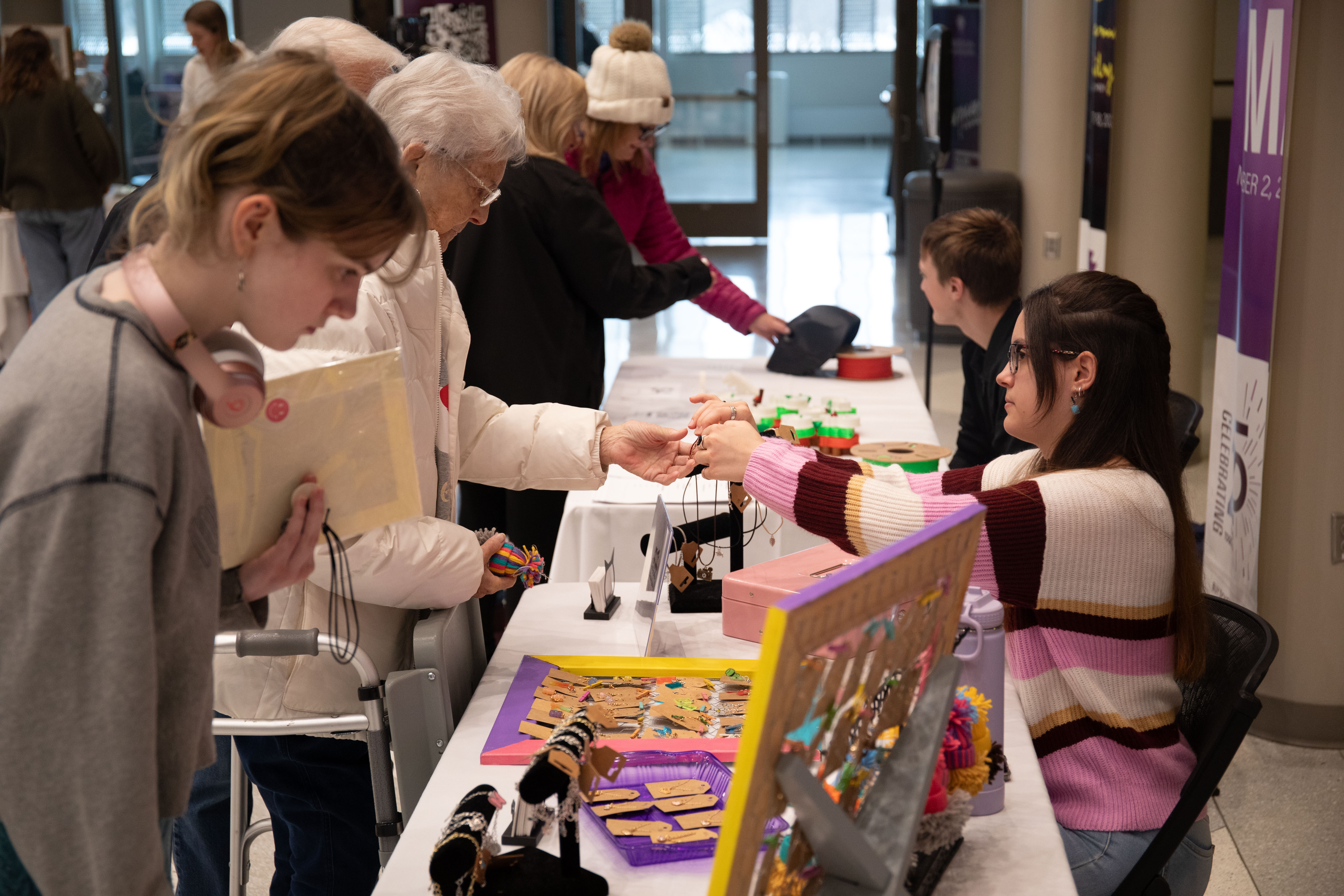 A student entrepreneur interacts with a customer at a vendor table during the UNI Student Small Business Holiday Market.