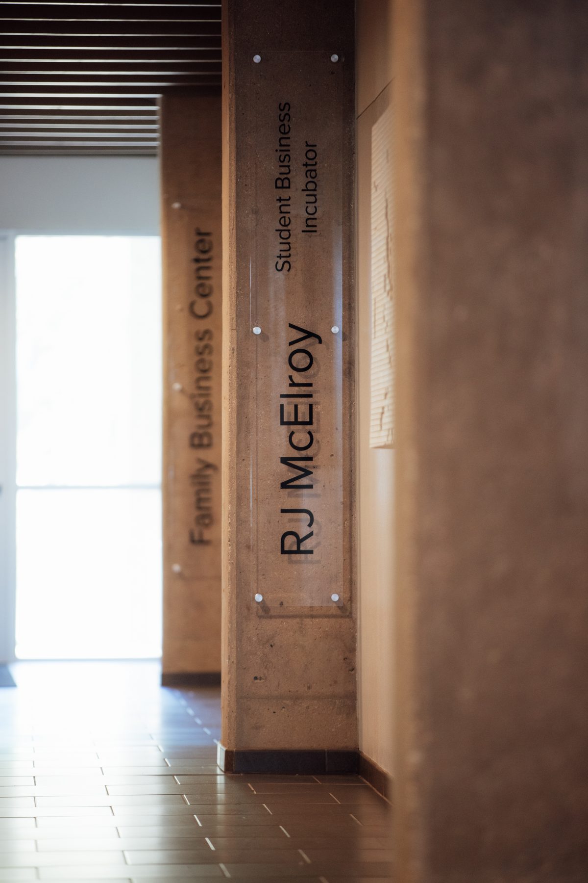 RJ McElroy Student Business Incubator and Family Business Center signage on pillars inside the JPEC building