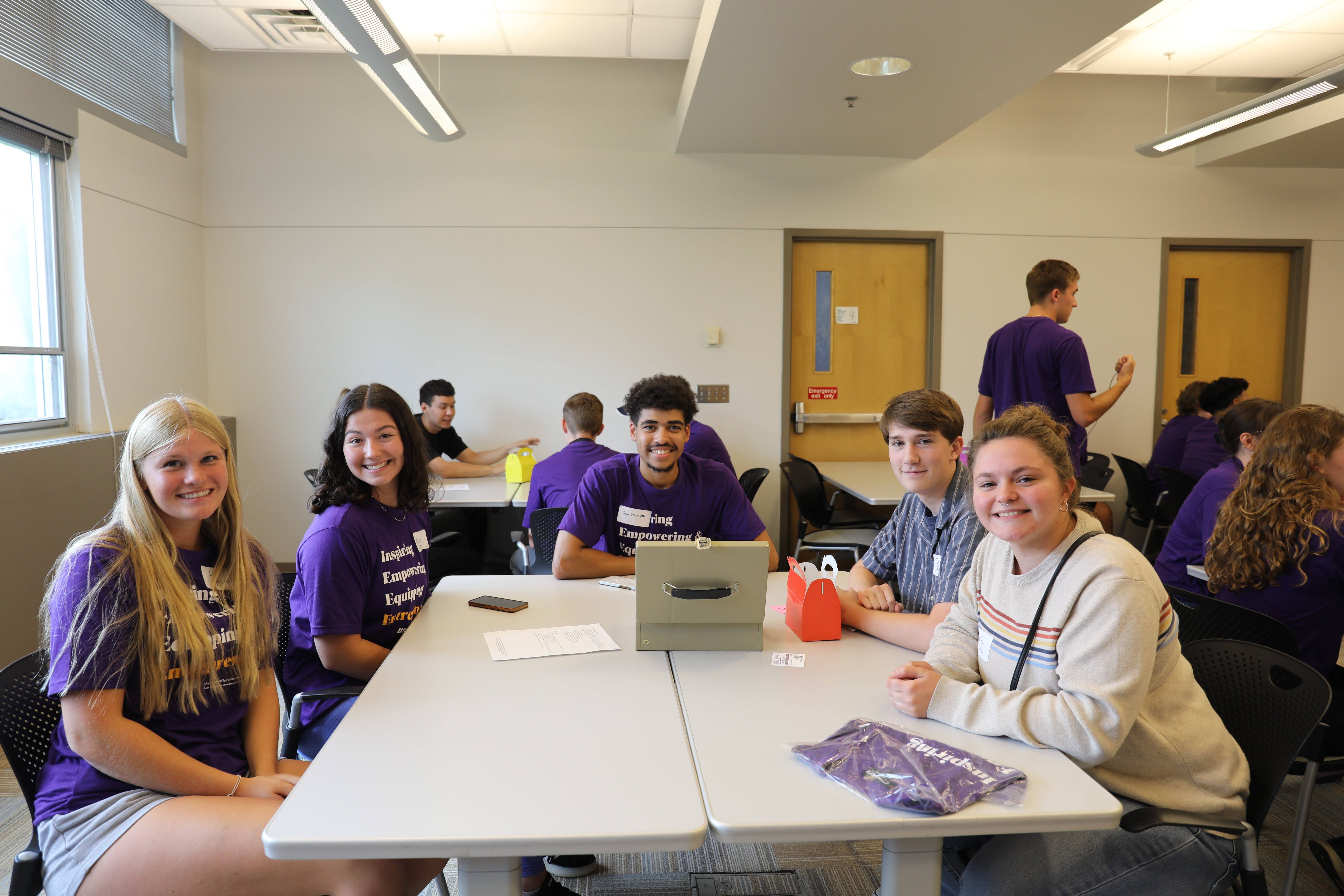 A large group poses together while sitting at a table at JPEC Connect smiling at the camera.