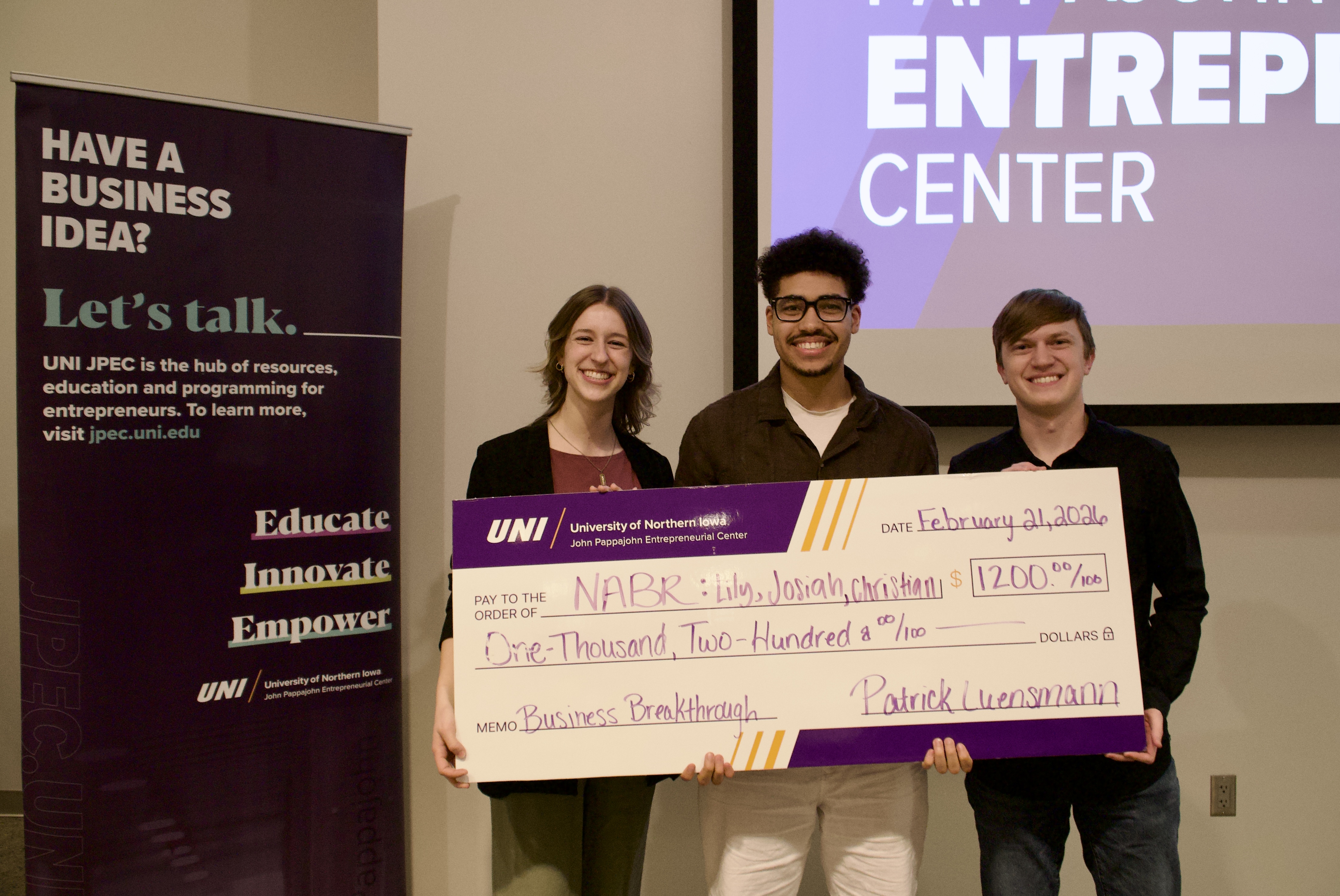 three students holding up check after winning pitch competition